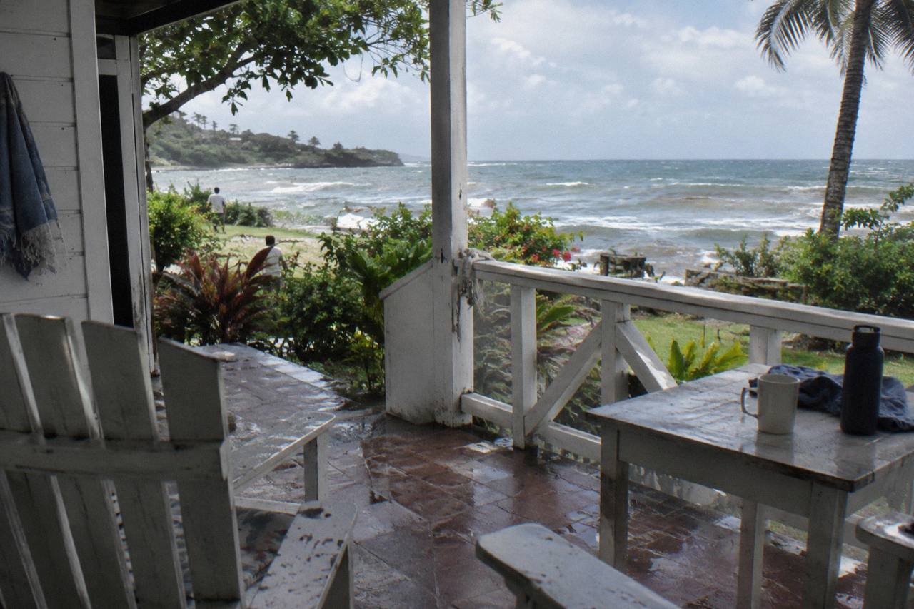 A quiet white veranda with wooden chairs opening onto a tropical garden and the sea (illustrative image, not the hotel)
